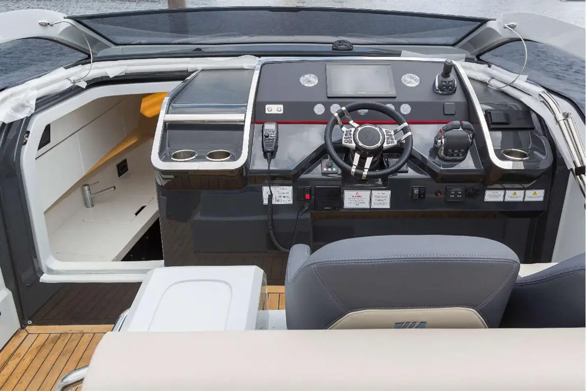 Luxury boat cockpit featuring a steering wheel, modern controls, touchscreen display, and ergonomic seating.